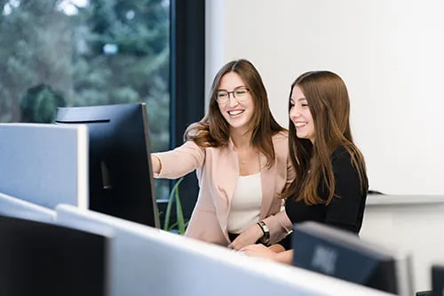 2 Mitarbeiterinnen im Gespr&auml;ch an einem Bildschirmarbeitsplatz im B&uuml;ro