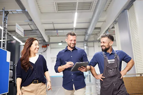 3 Mitarbeiter gehen durch einen Gang im Produktionsbereich