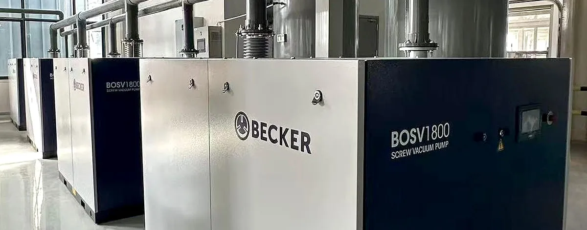 Row of oil-sealed Becker BOSV 1800 screw vacuum pumps connected by piping, installed inside an industrial production hall